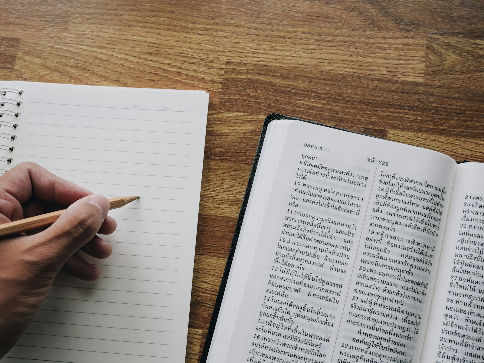 a person is writing on a book with a pencil