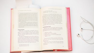 open book beside earphones on white surface